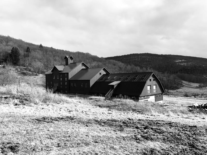 Black-and-white farmhouse and barn against the Catskill hills